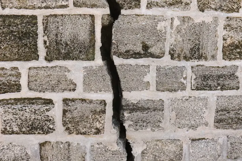 Fissure traversante dans un mur en maçonnerie de blocs, désordre à analyser après travaux